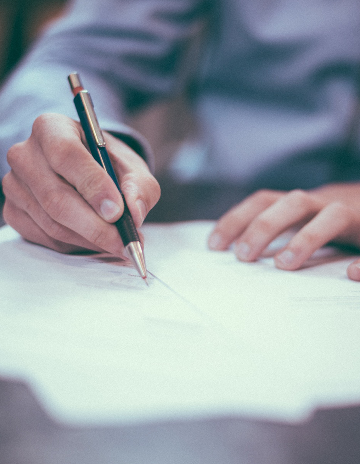 En person skriver på ett dokument med penna vid ett bord. Bilden symboliserar att du har rätt att agera – till exempel bestrida ett inkassokrav skriftligt.