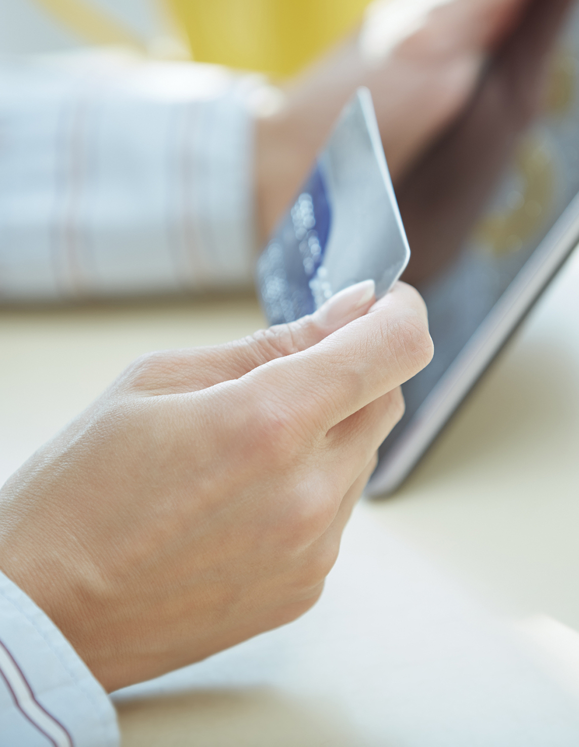 En person håller ett betalkort framför en surfplatta. Bilden symboliserar att du kan välja att betala ett inkassokrav digitalt för att lösa situationen.