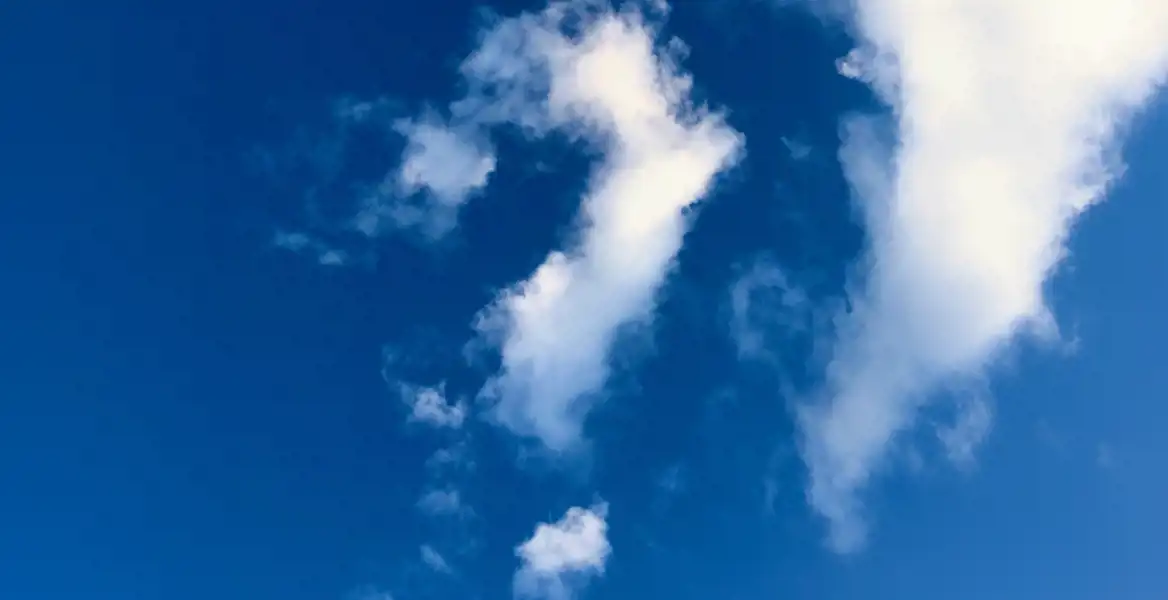 Ljusblå himmel med vita moln, där ett moln liknar ett frågetecken. Bilden symboliserar vanliga frågor och svar om inkassokrav – du är inte ensam om dina funderingar.